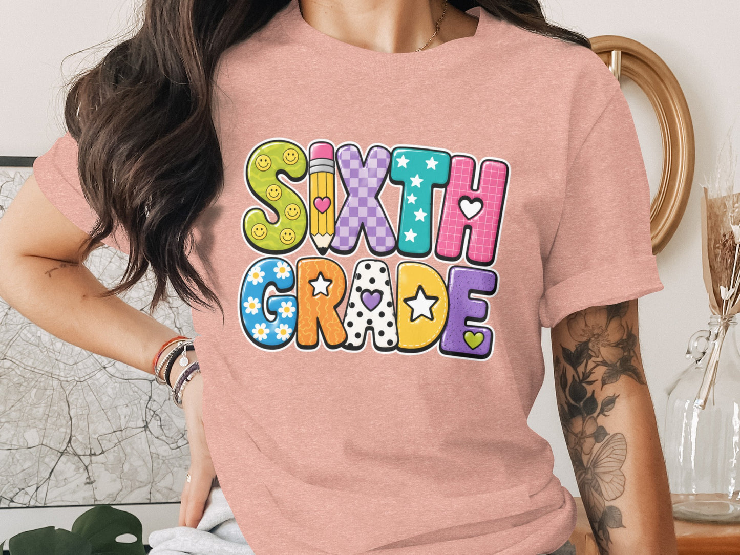 T-shirt with colorful "Sixth Grade" text featuring smiley faces, pencil, and stars.