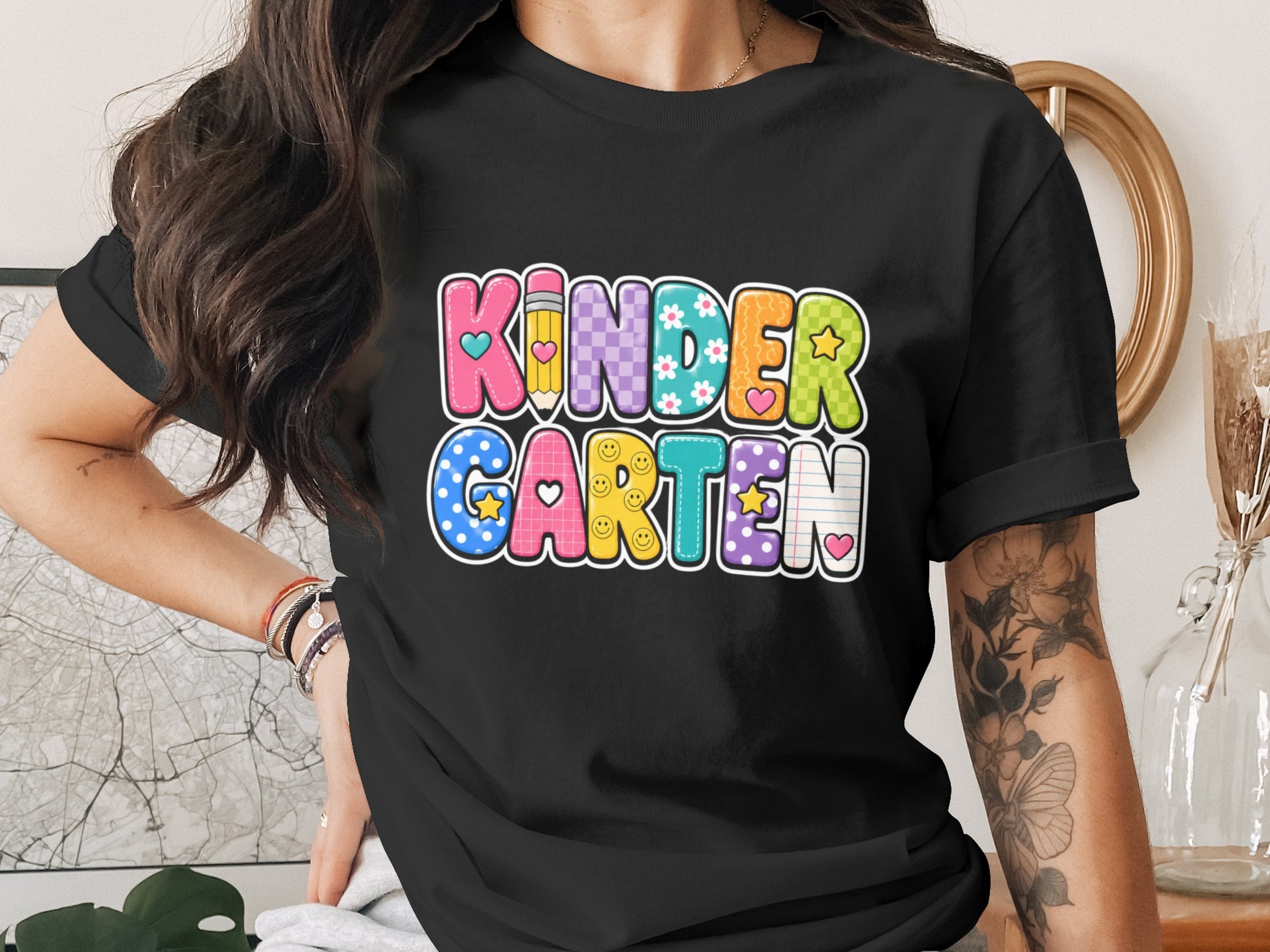 Colorful "KINDERGARTEN" text with a pencil and smiling faces on a black t-shirt.