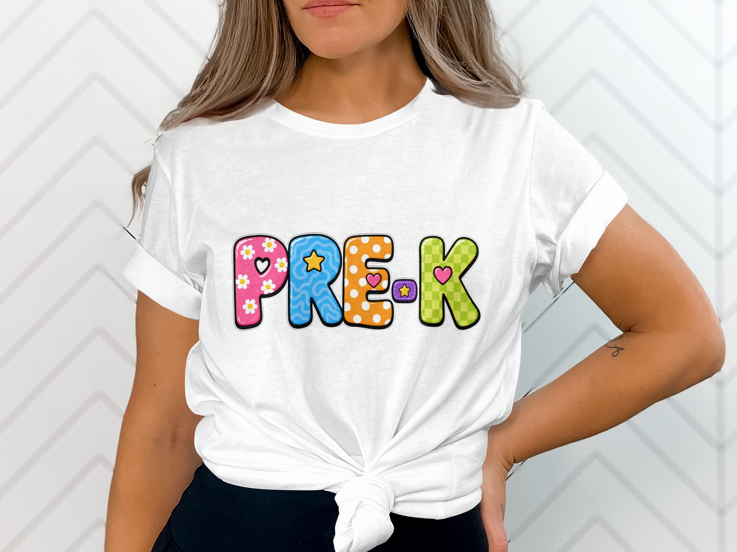 White t-shirt with colorful "PRE-K" text featuring patterns and hearts.