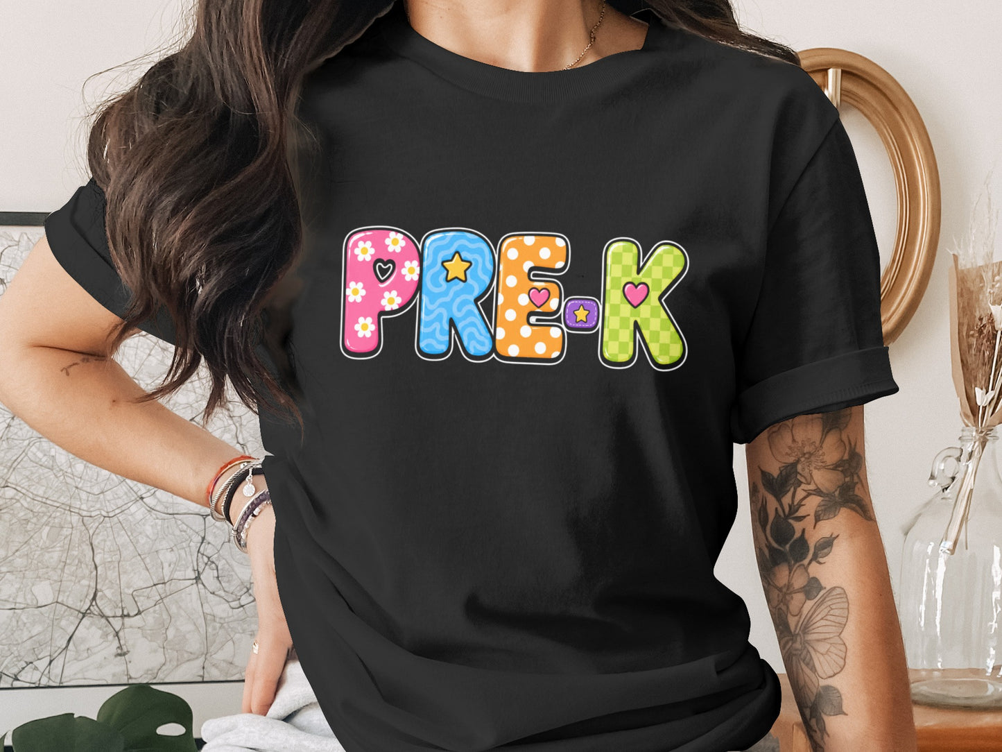 Black t-shirt with colorful "PRE-K" text graphic featuring flowers, stars, and hearts.