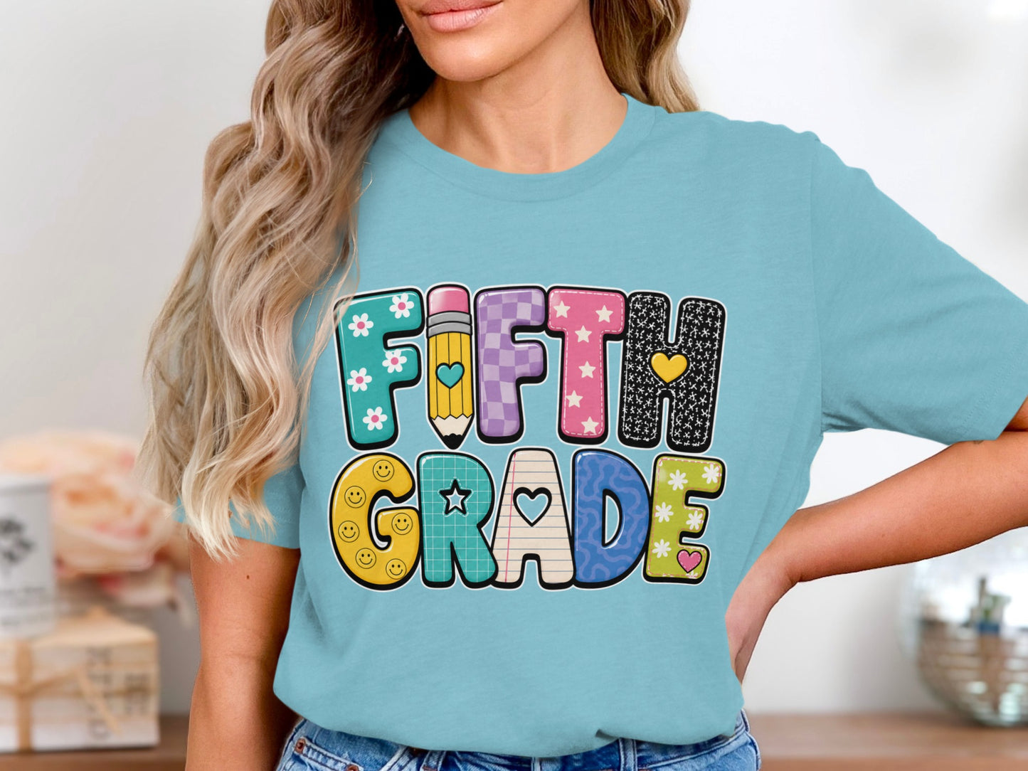 Fifth Grade text with smiley faces, flowers, and hearts on a blue t-shirt.