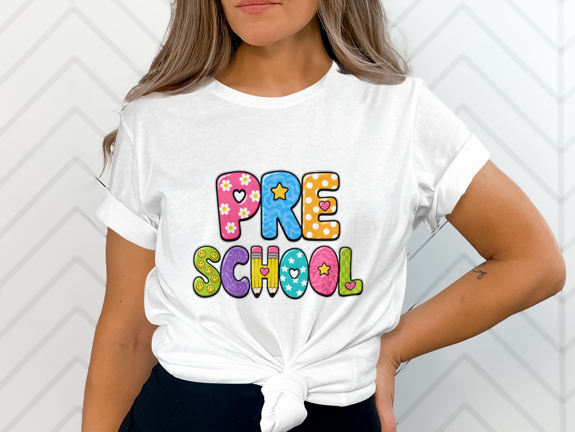 White t-shirt with "PRE SCHOOL" text in colorful, decorative lettering.