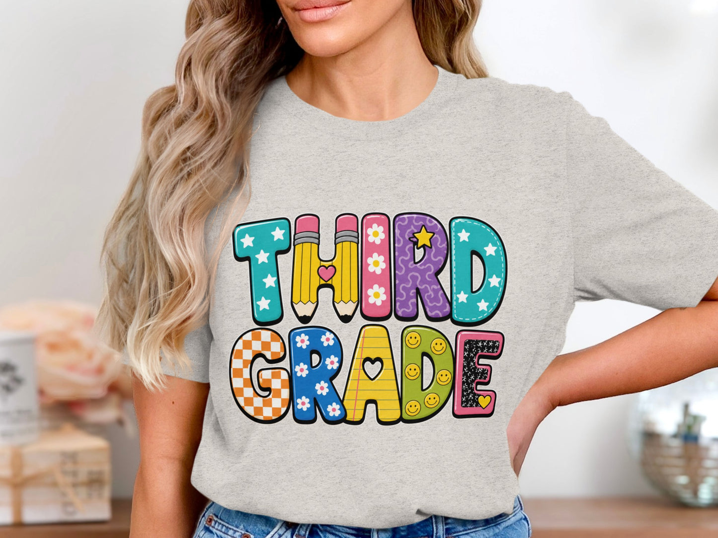 Third Grade text with decorative letters on a light grey t-shirt.