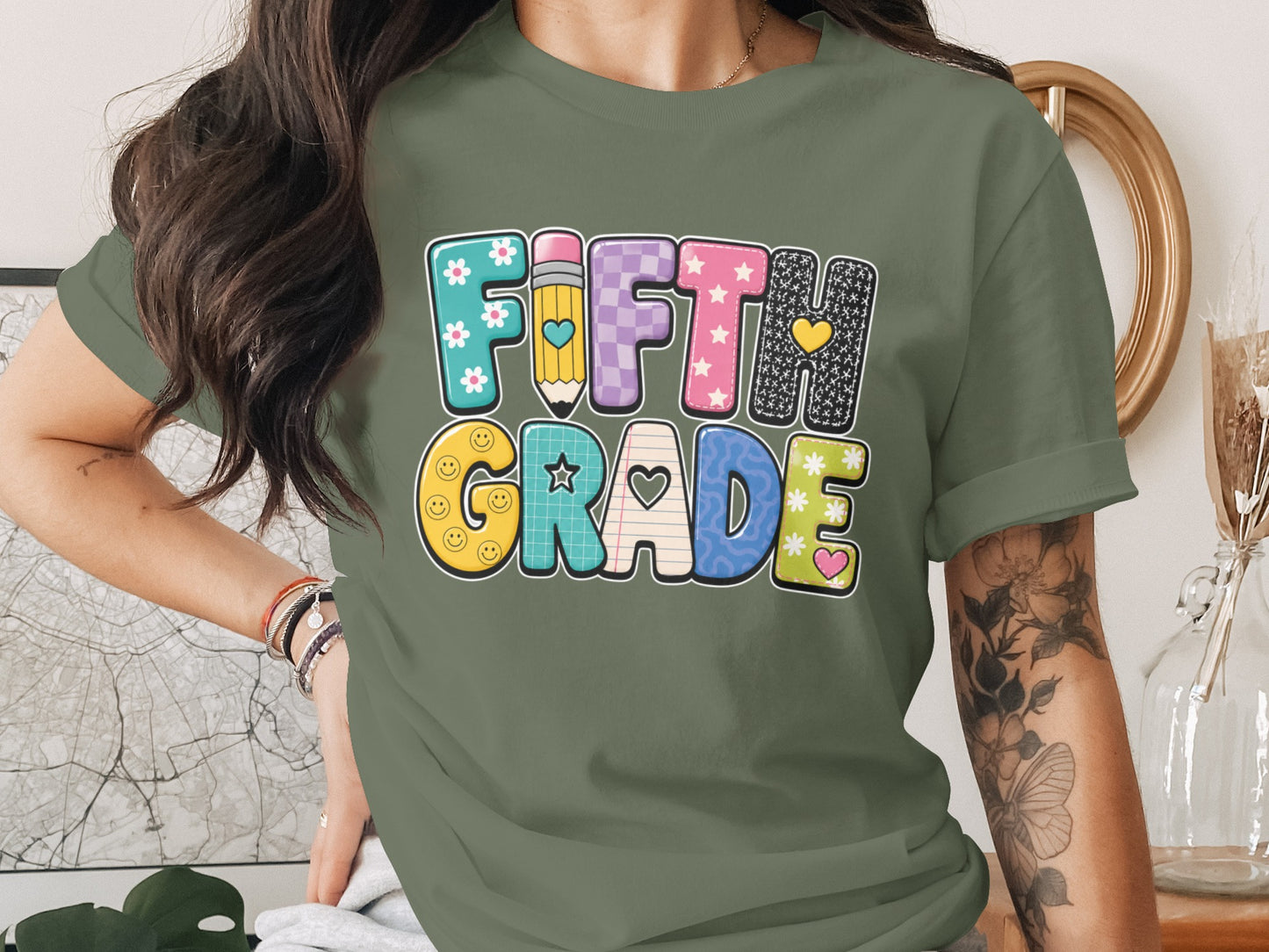 Green t-shirt with colorful "FIFTH GRADE" text and school-themed graphics.