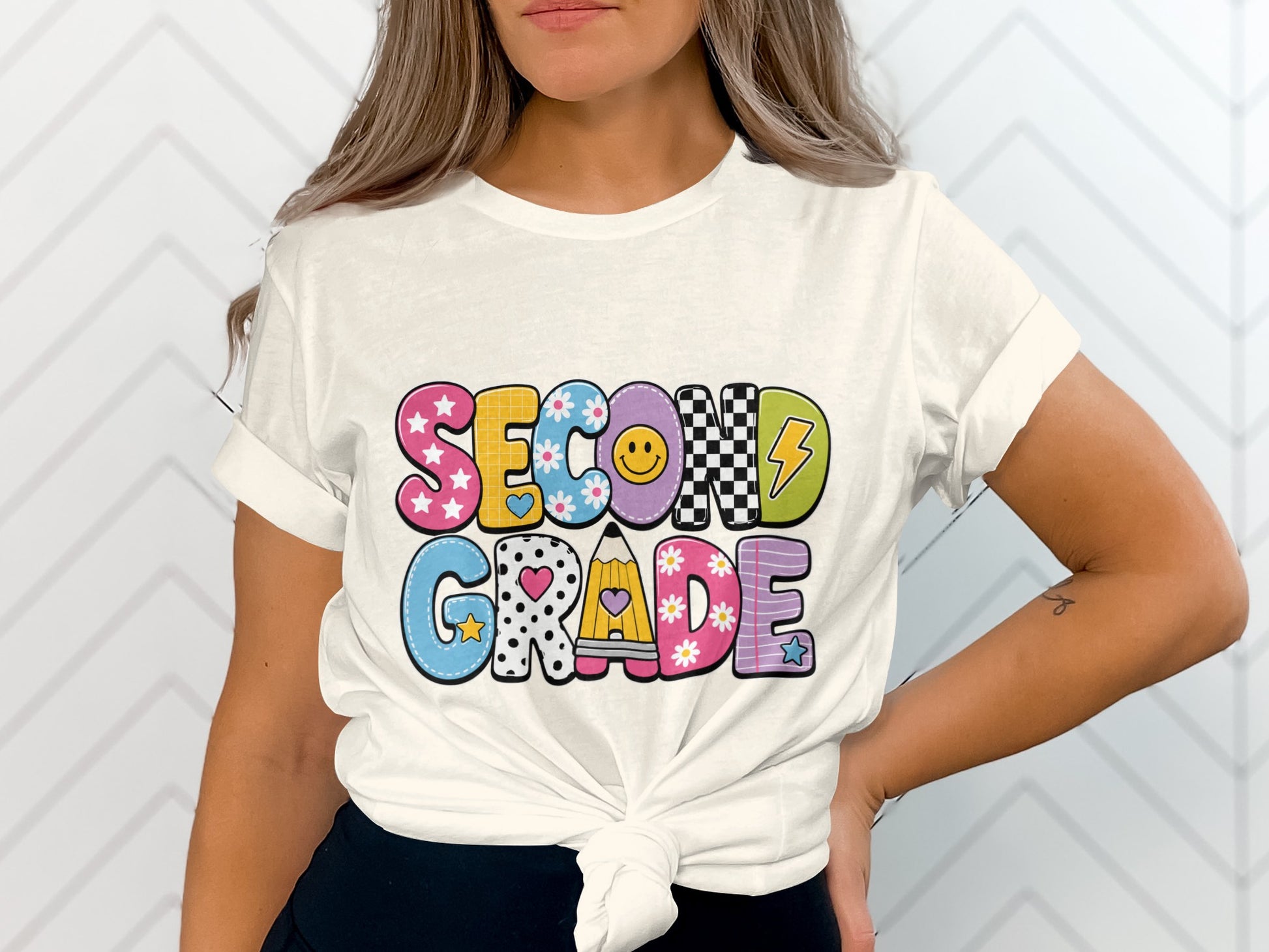 White t-shirt with colorful "Second Grade" text featuring stars, flowers, smiley face, and pencil.