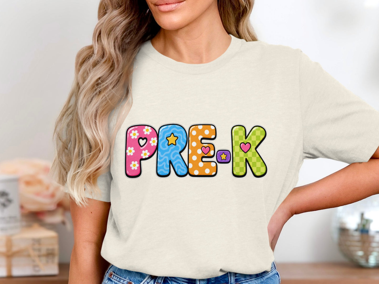 PRE-K text with colorful, patterned letters and hearts on a cream t-shirt.