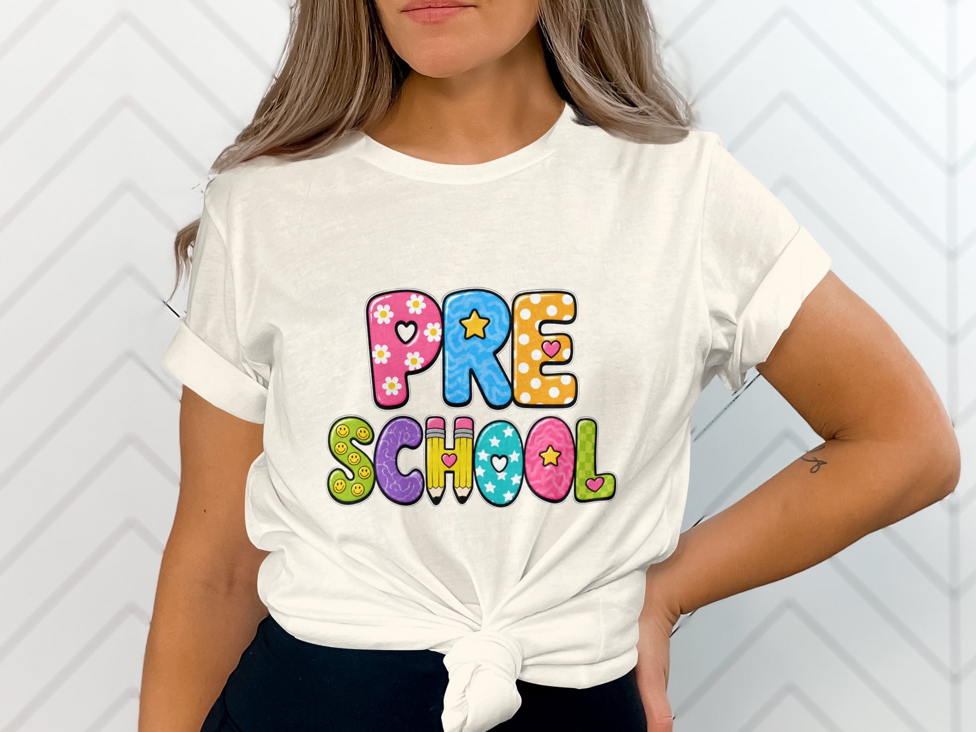White t-shirt with colorful "PRE SCHOOL" text and playful graphics.