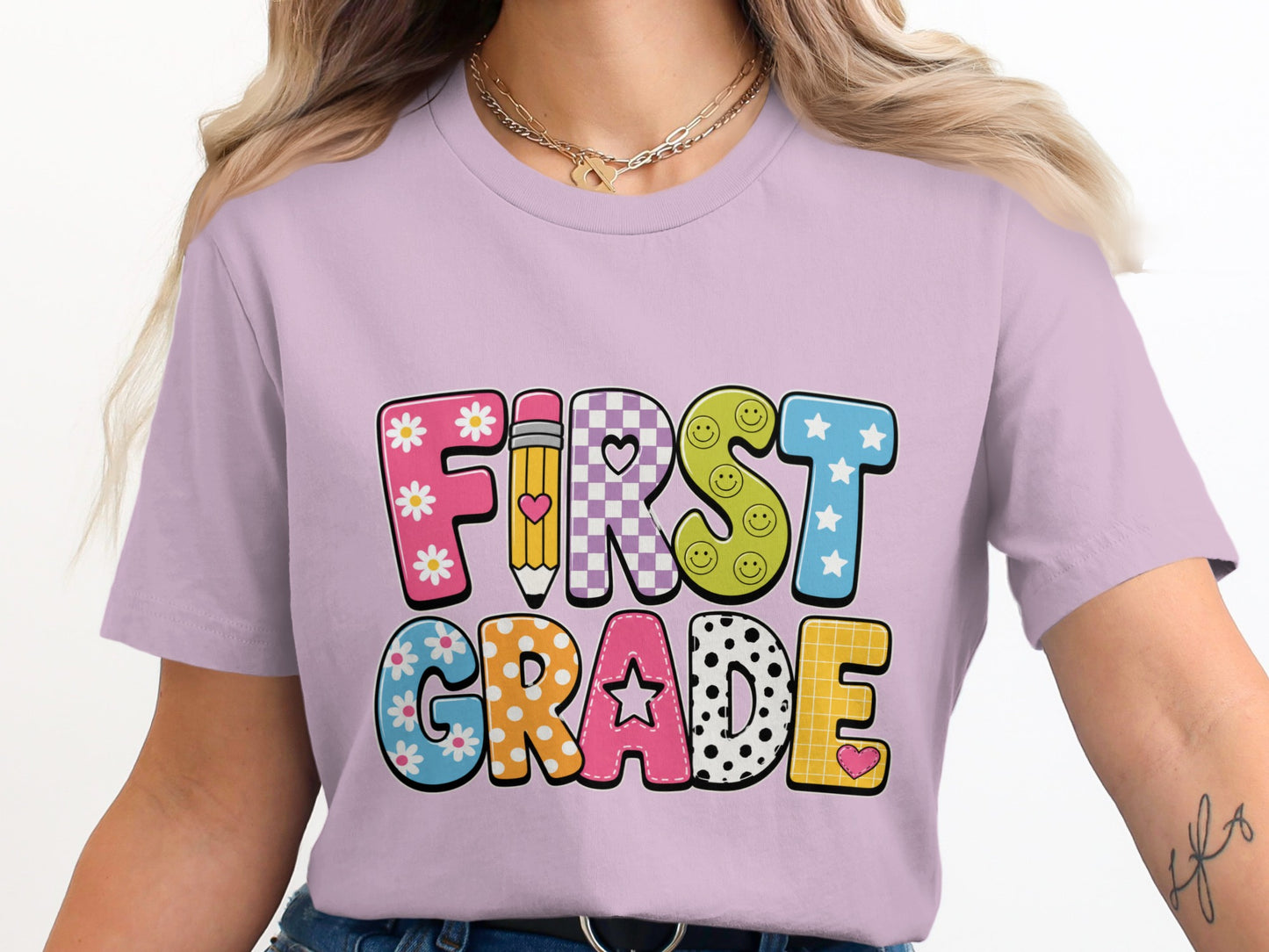 First Grade graphic on a light purple t-shirt with colorful patterned letters.