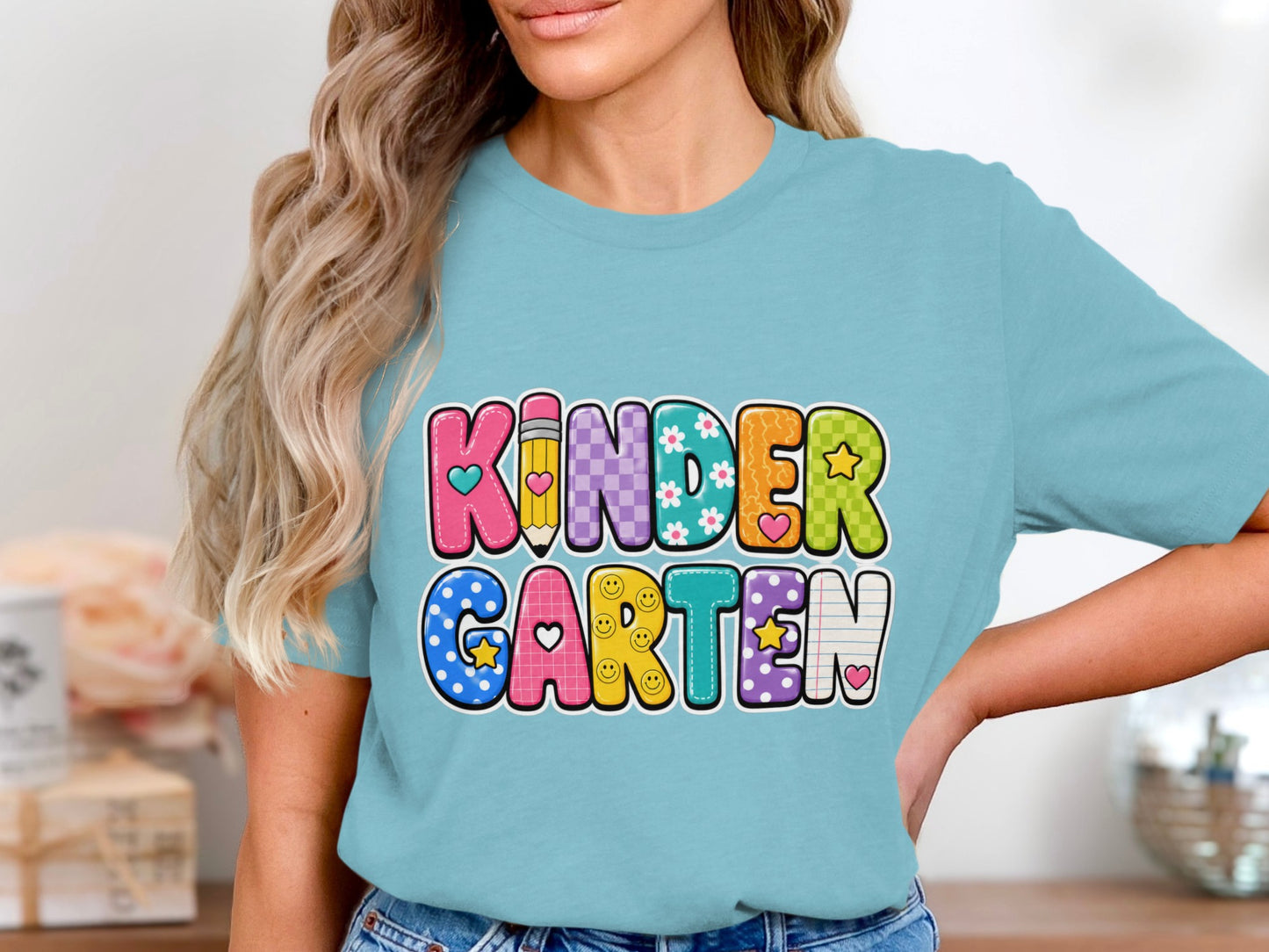 Bright, colorful "KINDERGARTEN" text graphic with school-themed elements on a light blue t-shirt.