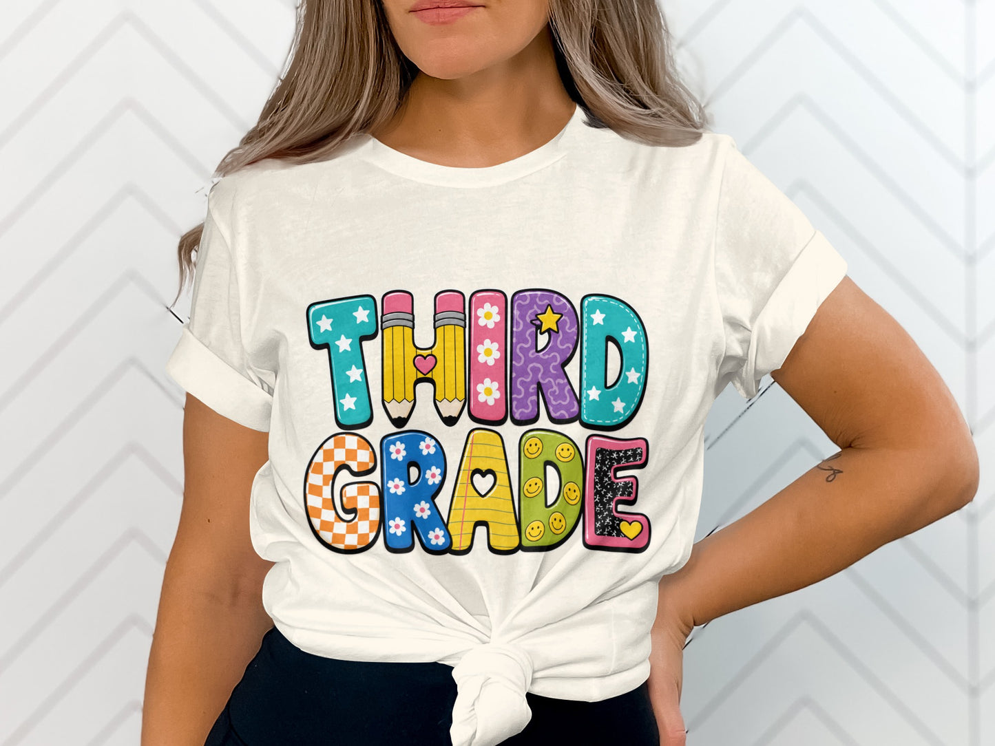 White t-shirt with "THIRD GRADE" text in colorful, patterned letters.