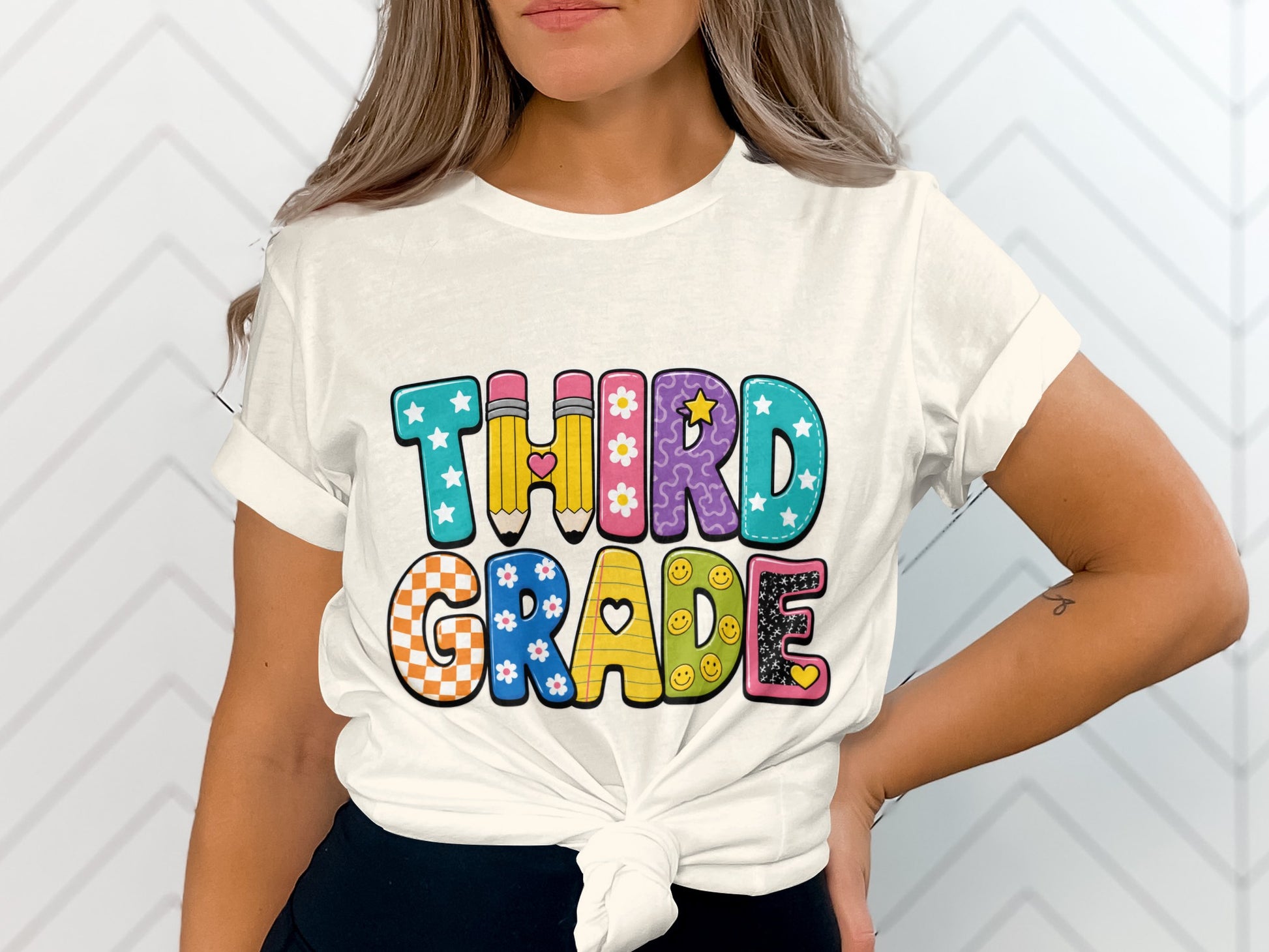 White t-shirt with "THIRD GRADE" text in colorful, patterned letters.