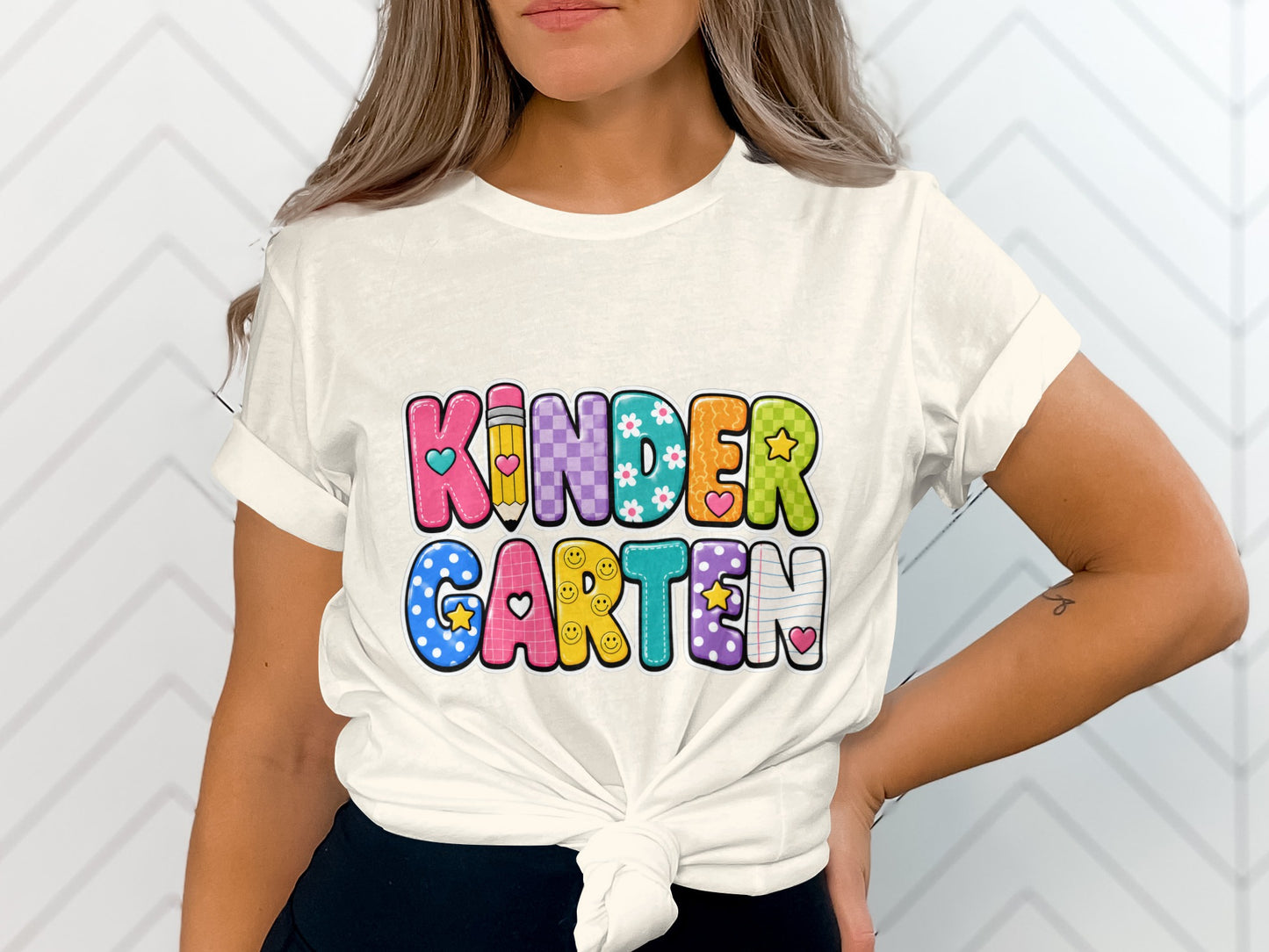 White t-shirt with colorful "Kindergarten" text and assorted patterns.