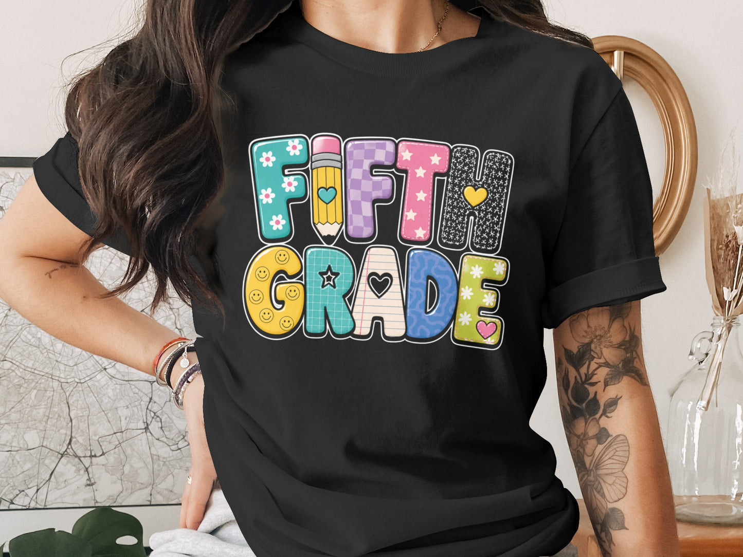 Black t-shirt with "Fifth Grade" text in colorful, patterned letters.