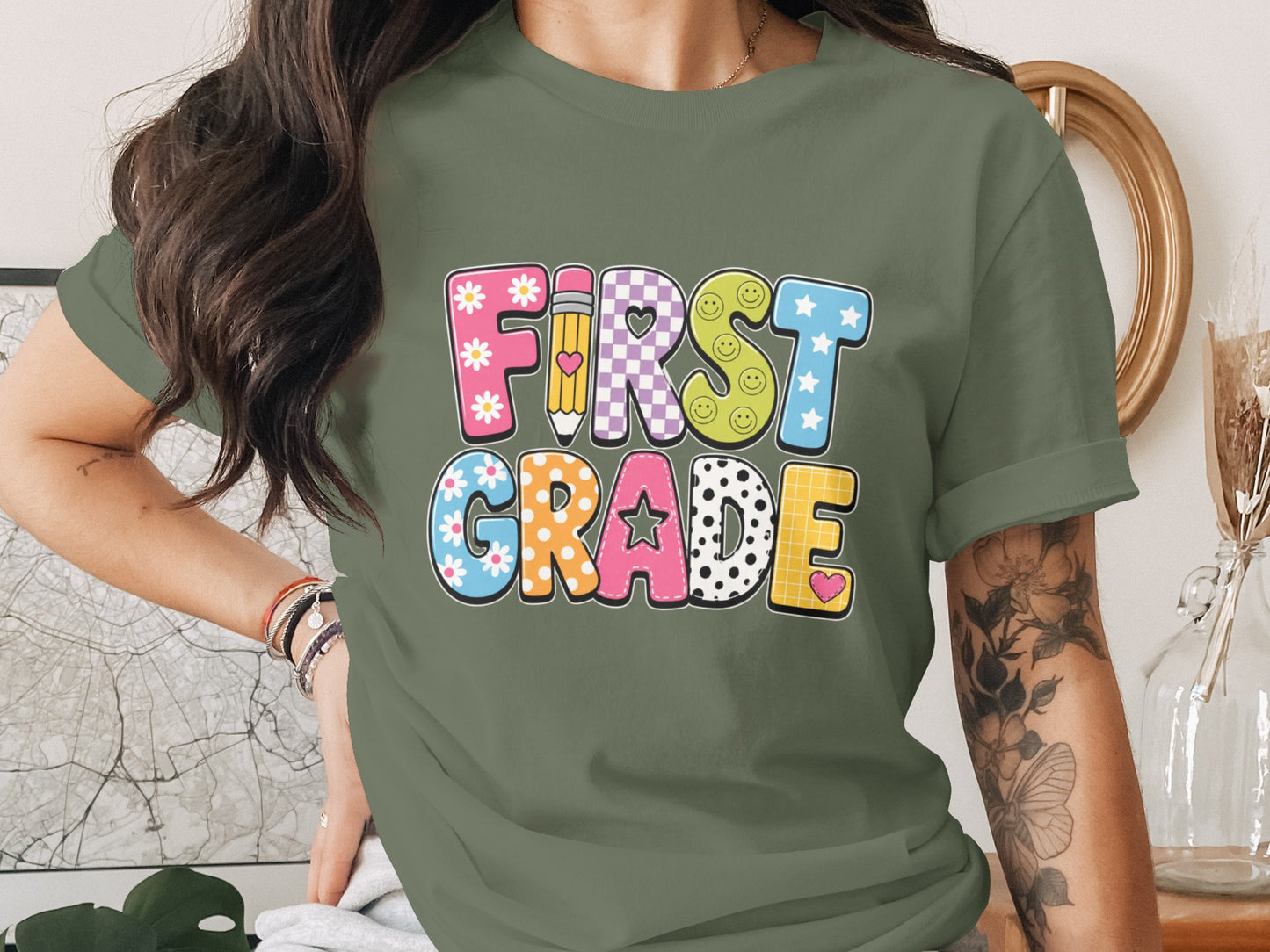 "First Grade" text with colorful patterned letters and school elements on a green t-shirt.