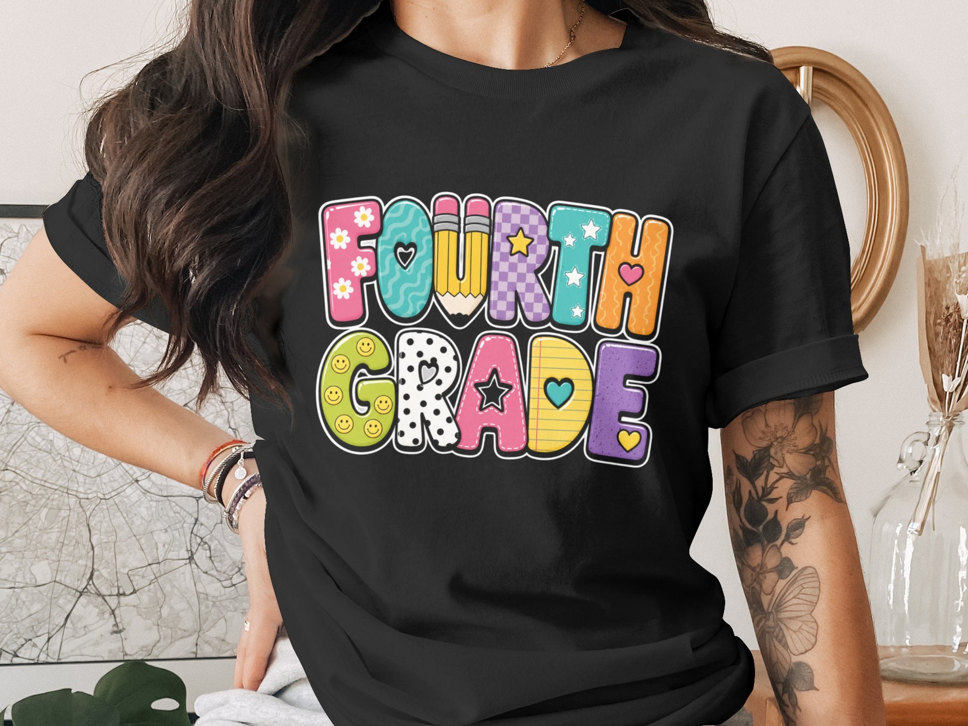 Black t-shirt with colorful "Fourth Grade" text featuring school-themed icons.
