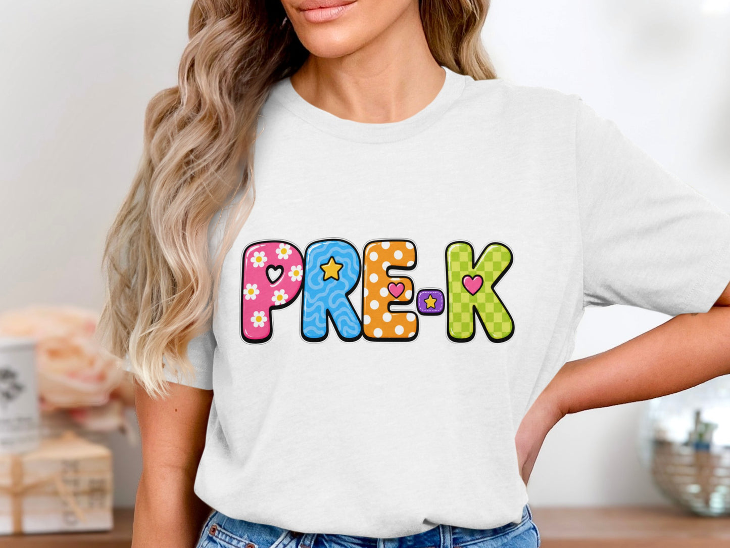 White t-shirt with colorful "PRE-K" text featuring floral, star, polka dot, and checkered patterns.