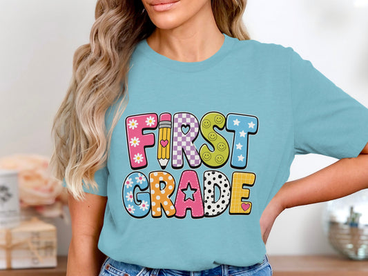 "First Grade" graphic in bold, colorful, patterned letters on a teal t-shirt