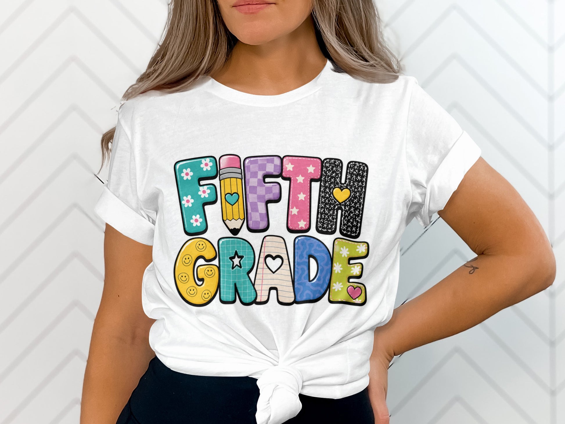 White t-shirt with colorful "FIFTH GRADE" text and playful designs.