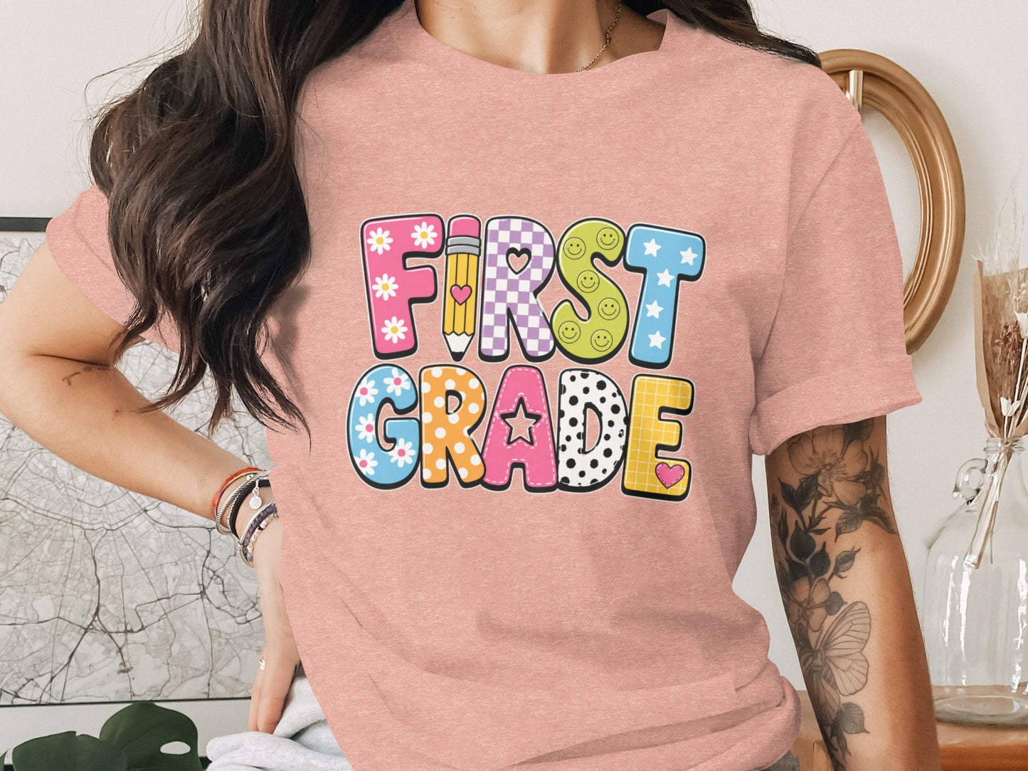 Pink t-shirt with "First Grade" in colorful block letters with fun patterns.